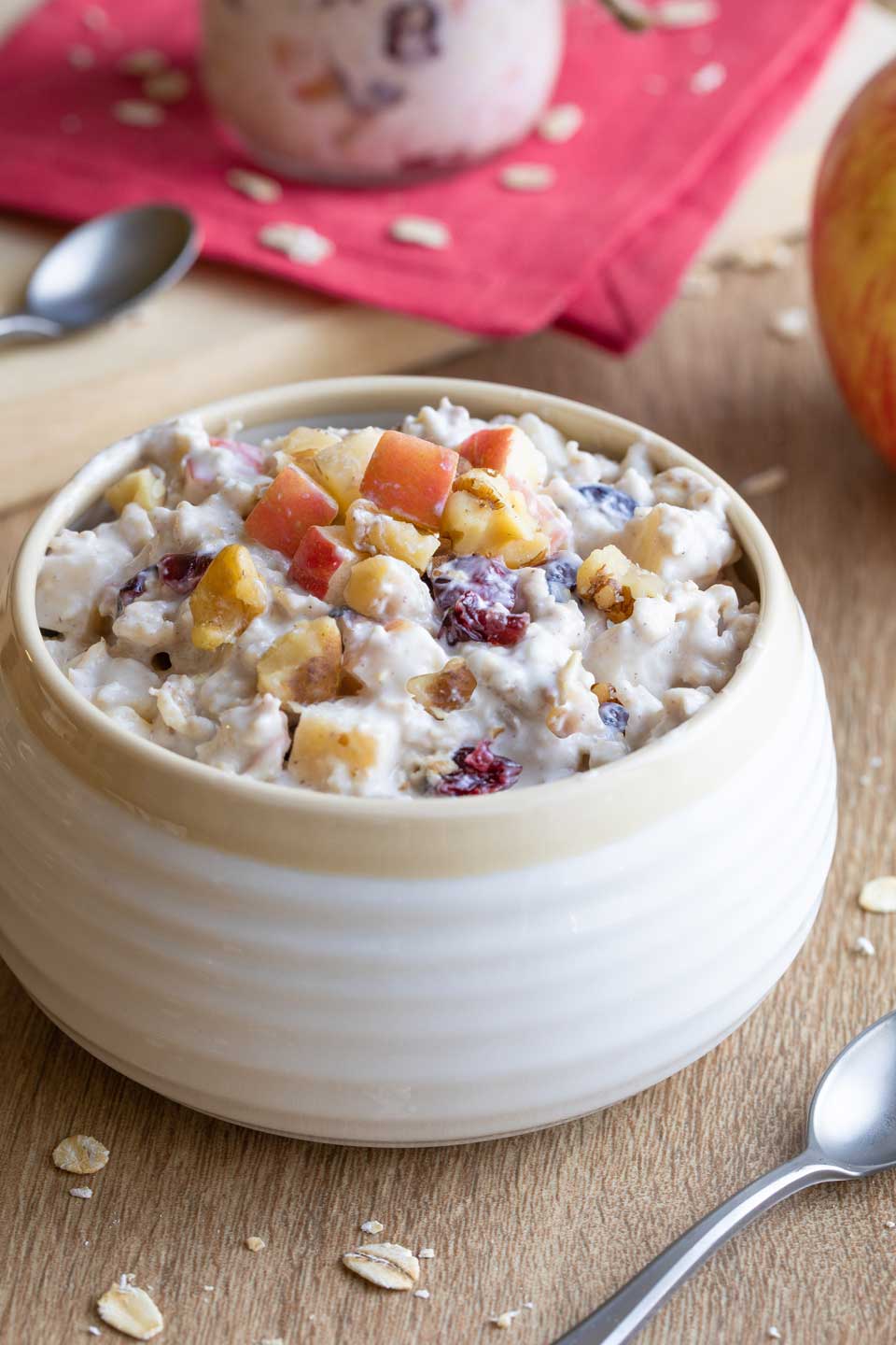 The overnight Oats in a bowl instead of a meal prep jar, with an apple and a few raw oats nearby decoratively.