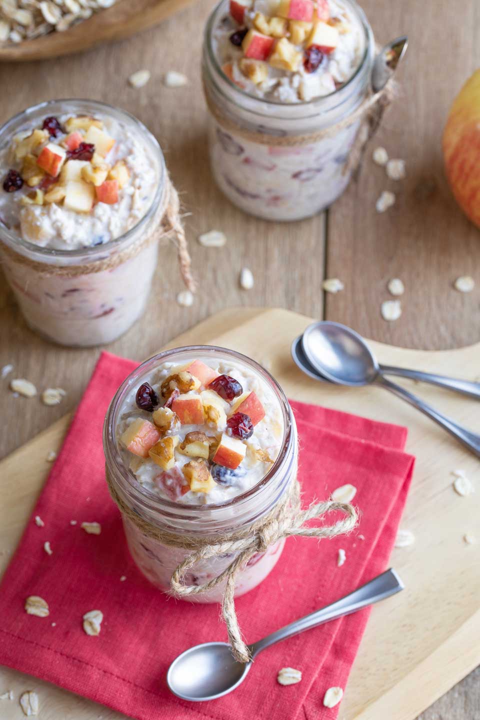 Overview of three filled meal prep jars, each with extra apples and nuts on top for a pretty presentation.