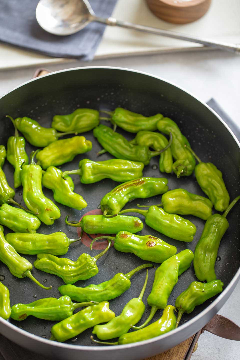 Overhead of skillet full of peppers just beginning to blister with a few brown spots.