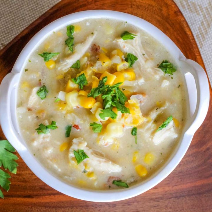 overhead of this chowder in a white bowl on a wooden triangular plate