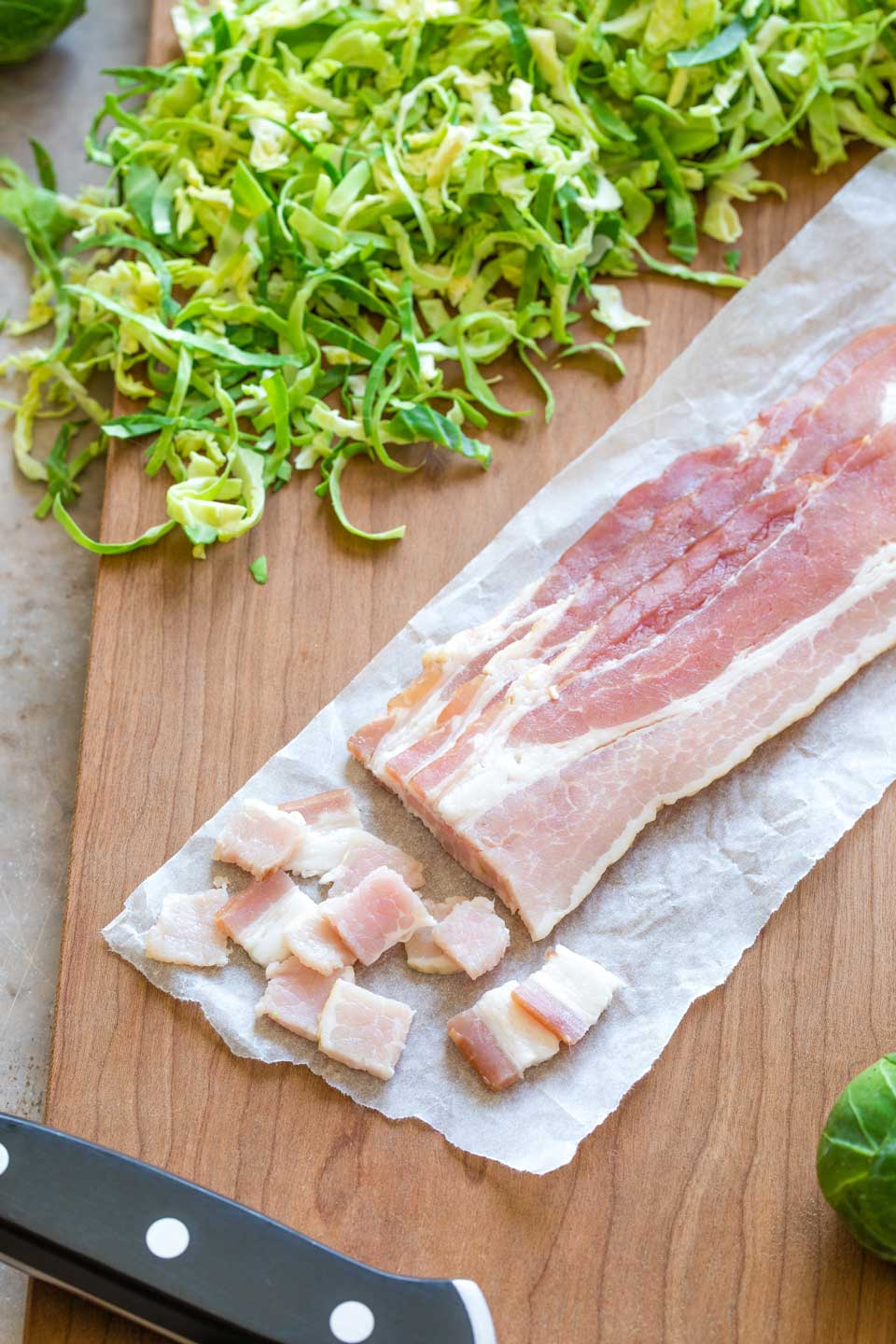 3 slices of bacon just beginning to be diced on cutting board.