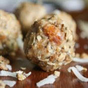 Closeup of one energy ball with a couple of moist dates right in the front, and bits of coconut and chia seeds scattered nearby.