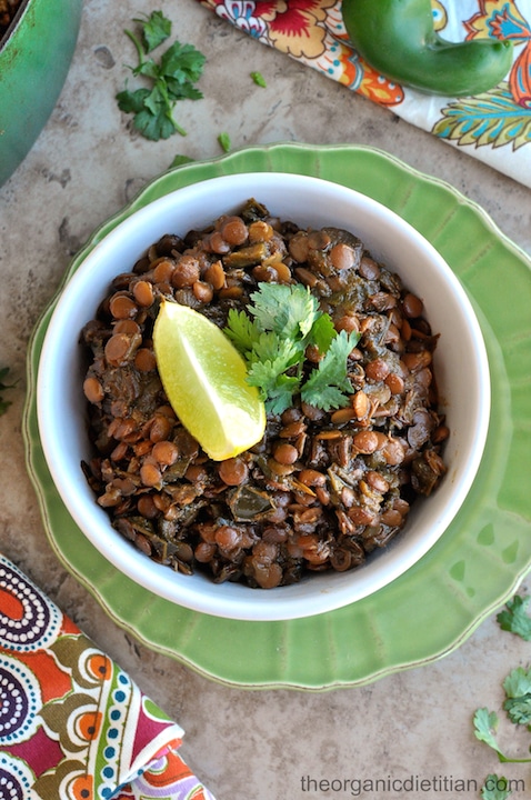 Overhead of chili in white bowl on green scalloped plate, surrounded by colorful napkins.