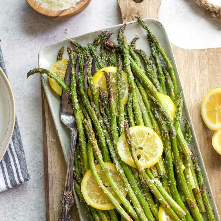 Asparagus after grilling, served on platter with lemon slices and sprinkling of parmesan.