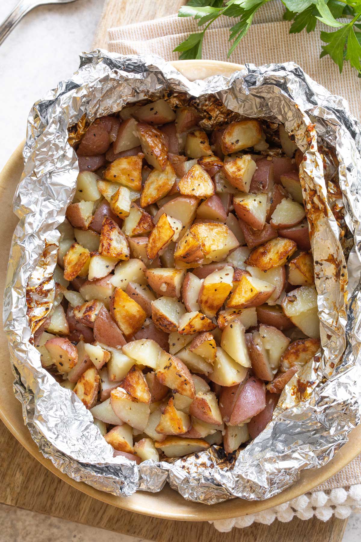 Overhead of foil packet, opened to reveal potatoes inside.