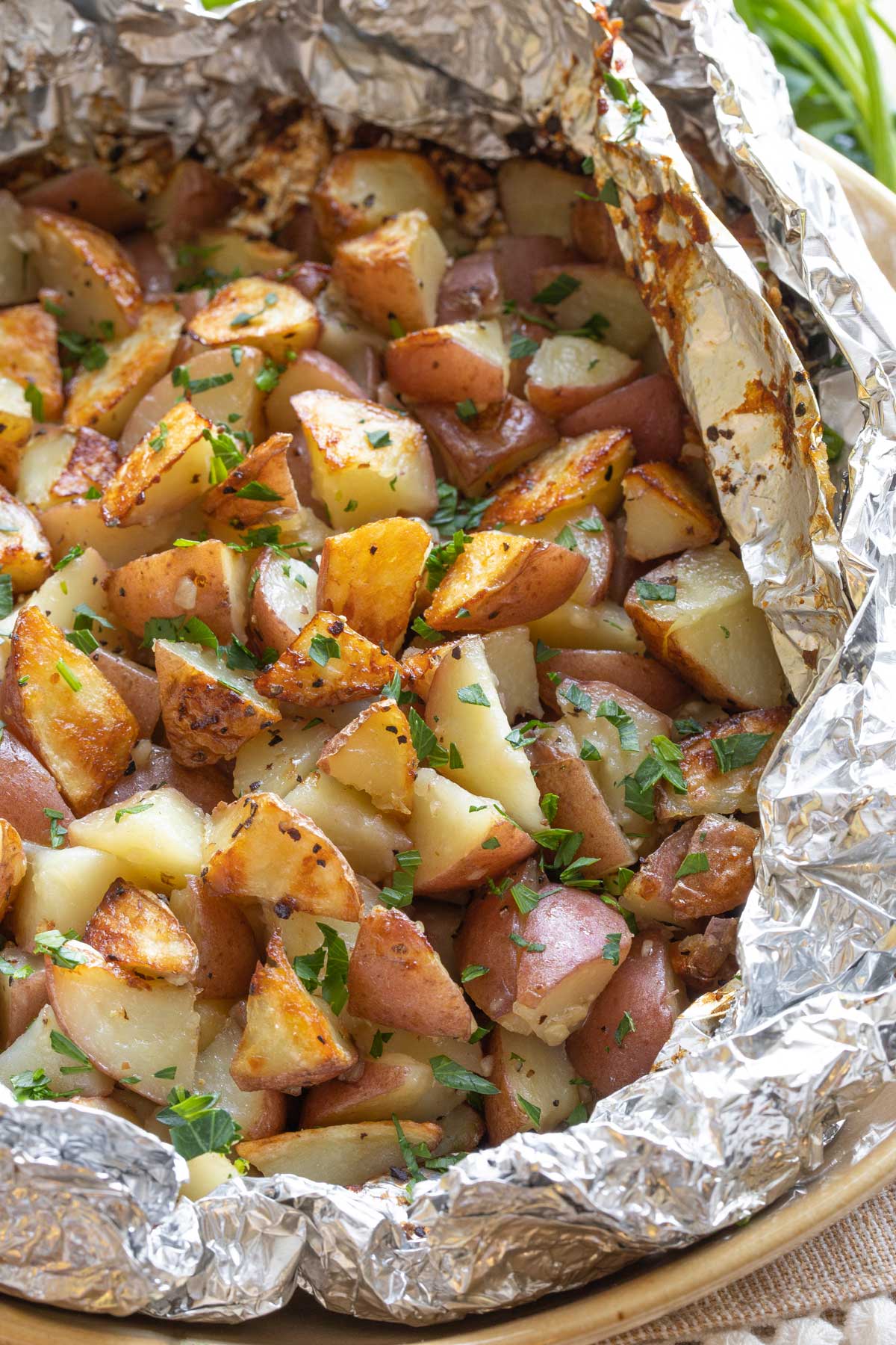 Closeup of potatoes in foil pack, opened and sprinkled with parsley.