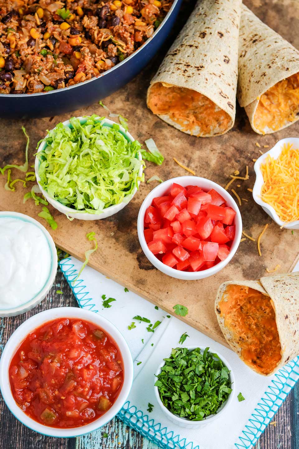 healthy toppings next to tortillas and pan of Mexican healthy ground beef recipe