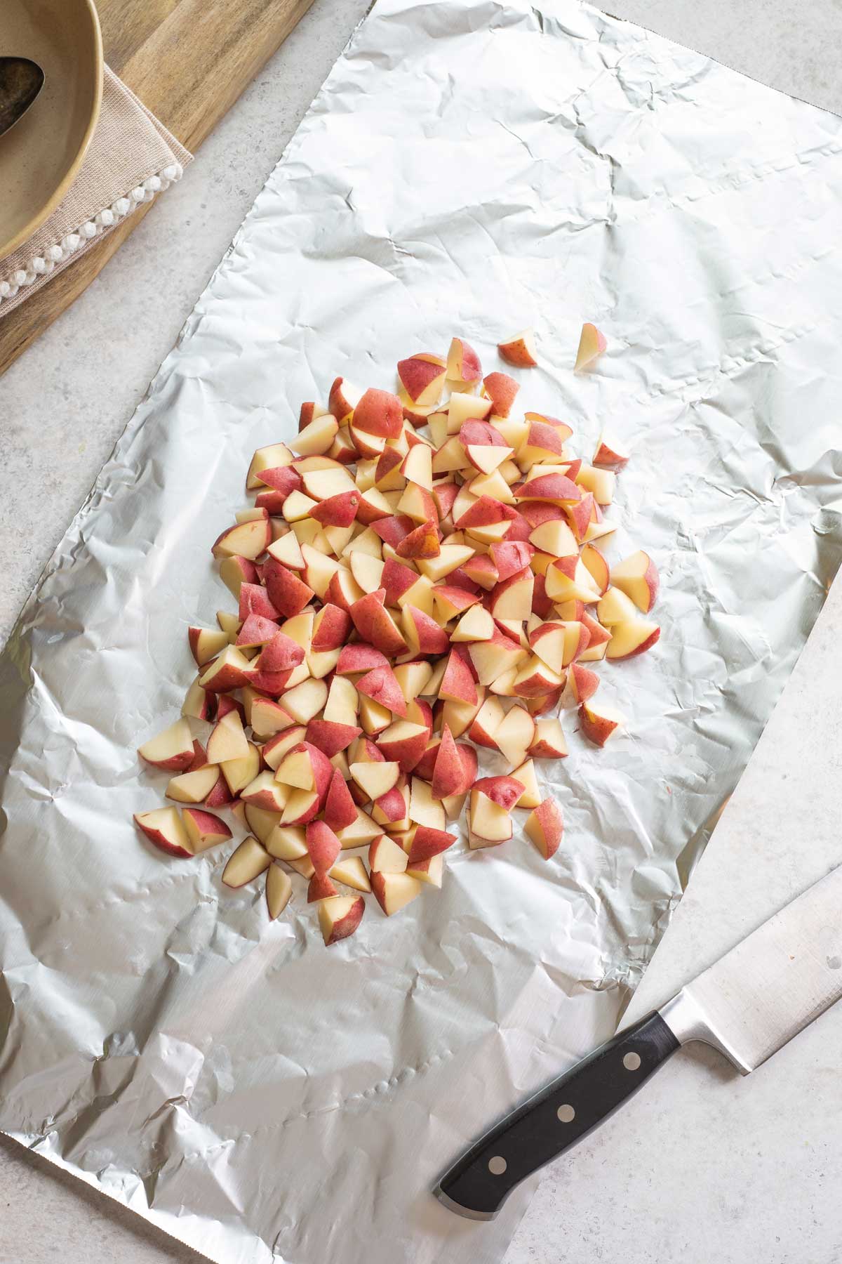 Chopped potatoes in center of large piece of foil with knife at side.