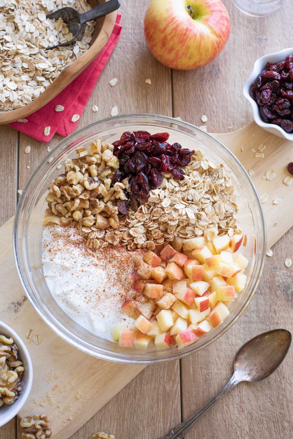 Step 1 of making Apple Overnight Oats, with all ingredients in a glass bowl but not yet stirred together.