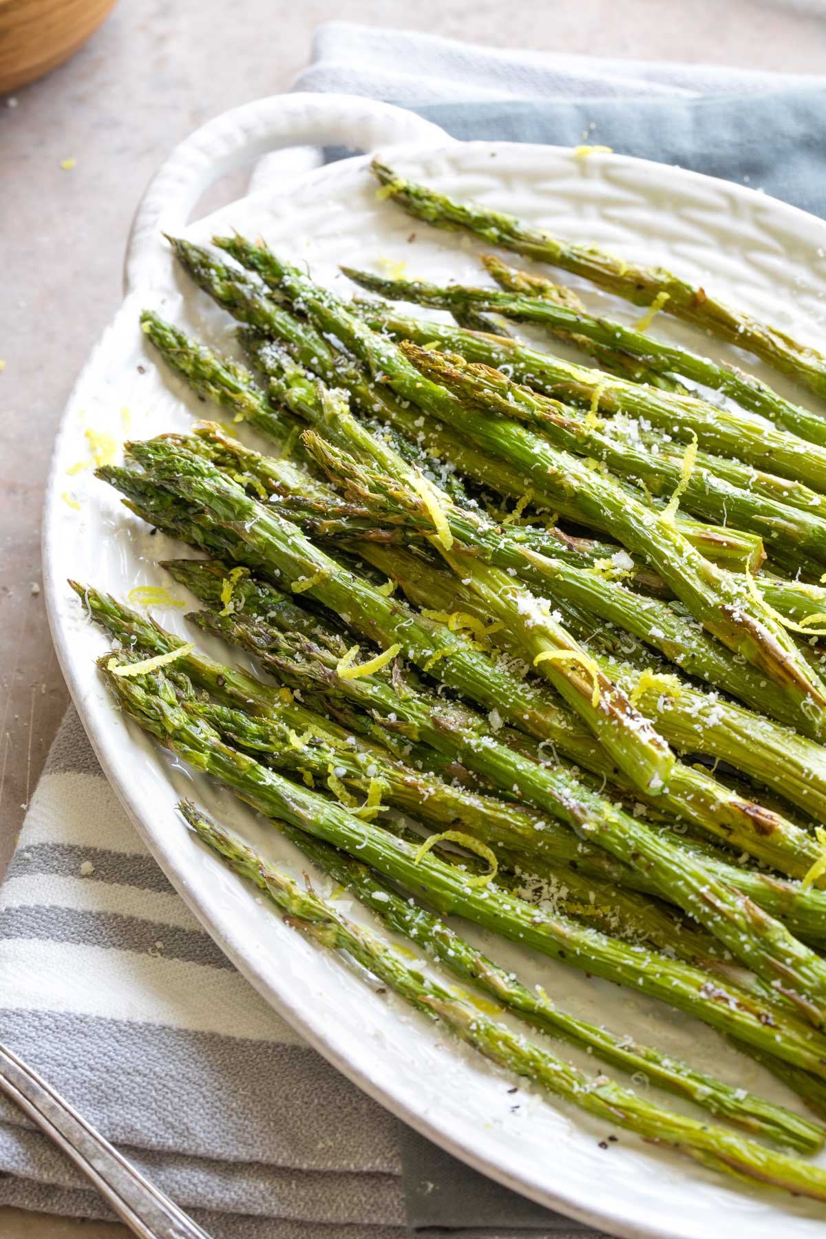 Air fried asparagus served on white platter with parmesan cheese and lemon zest.