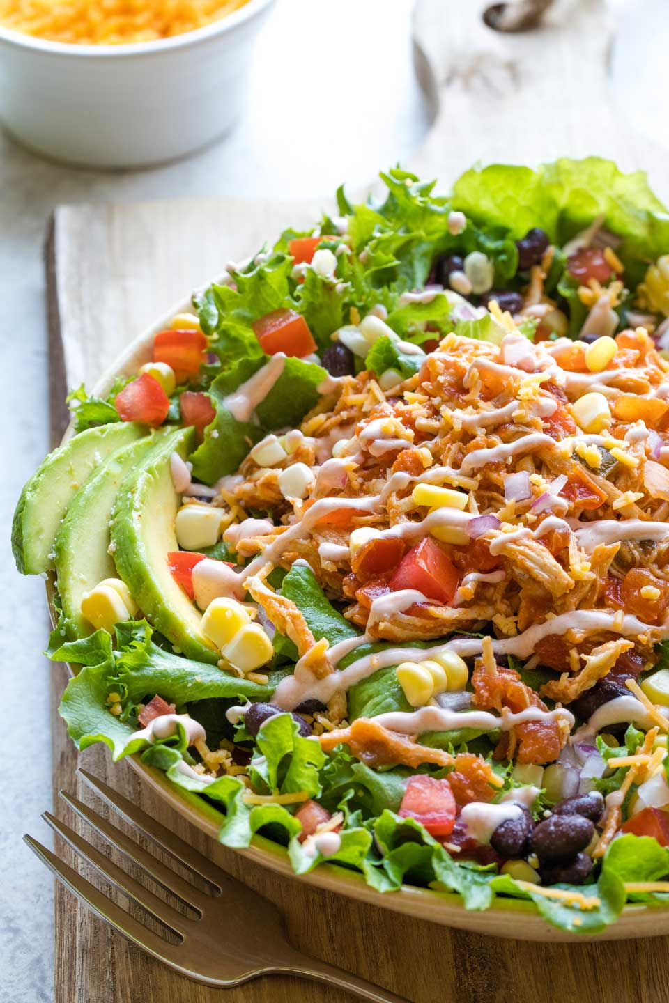 Serving suggestion showing the shredded chicken piled on top of a loaded taco salad.