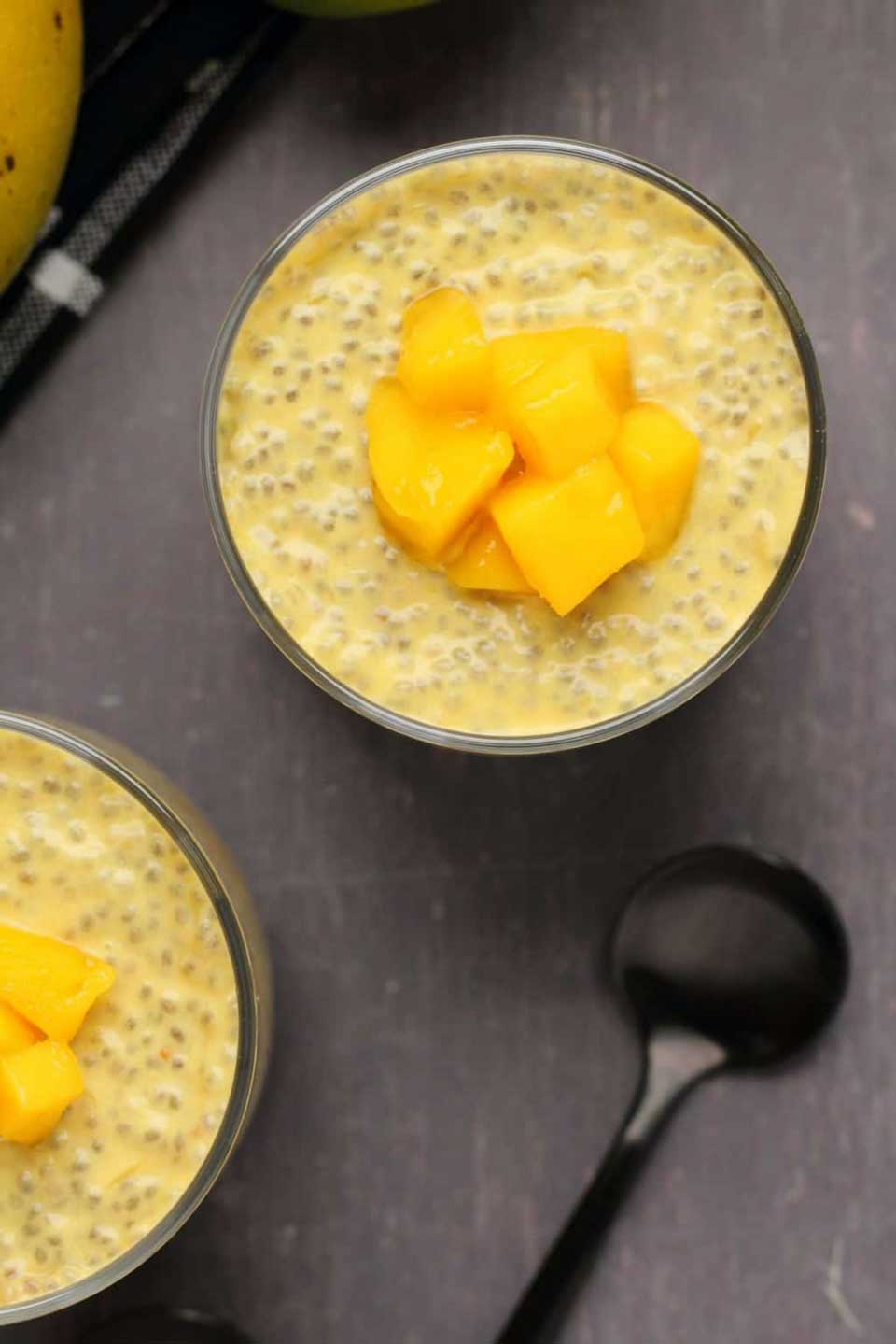 Overhead of one serving, garnished with mango chunks, with a second serving and black spoons nearby.