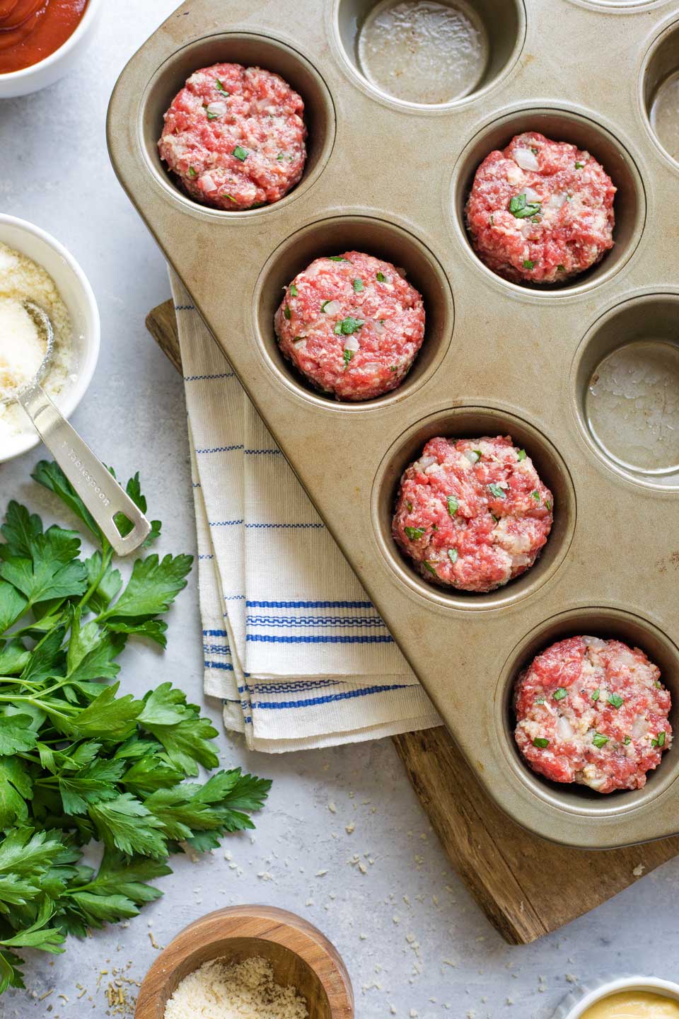 Overhead of muffin tin with some of the meatloaf minis placed inside, but some open spots remaining.