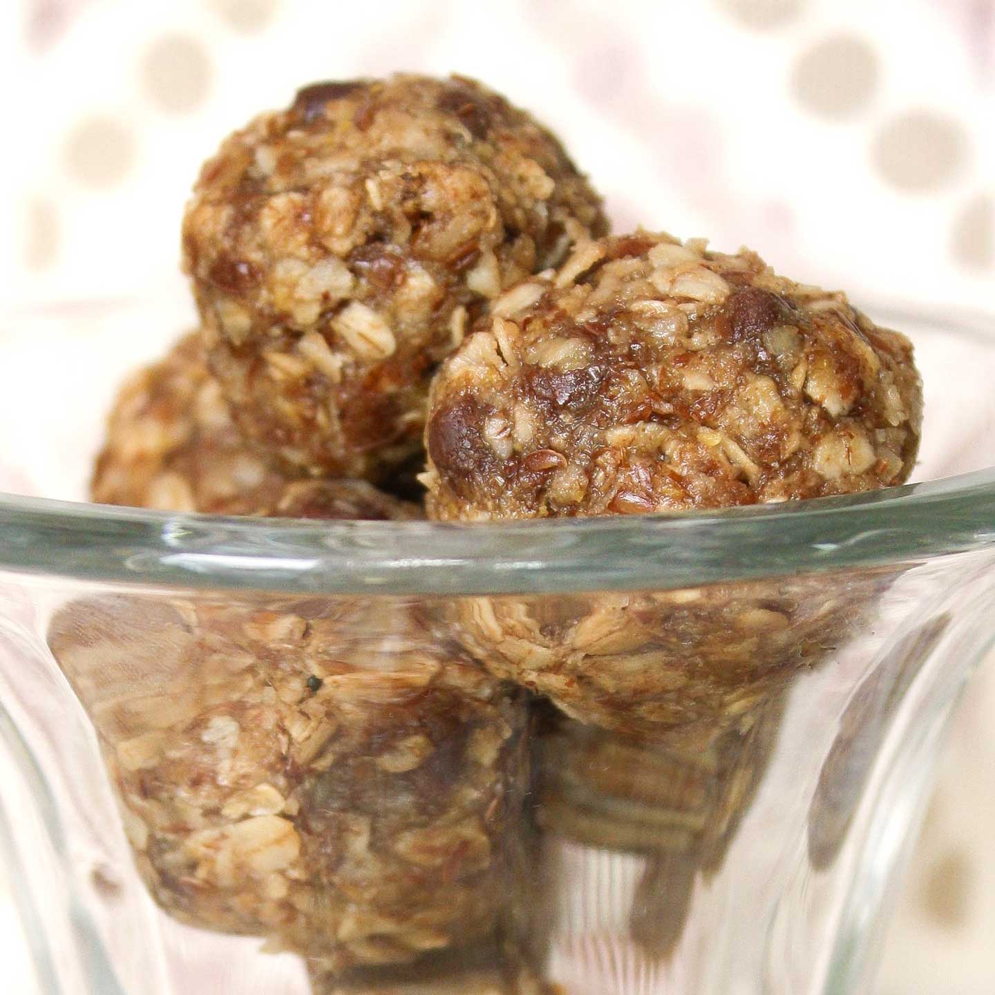 Several energy balls stacked in a tall, clear glass parfait cup.