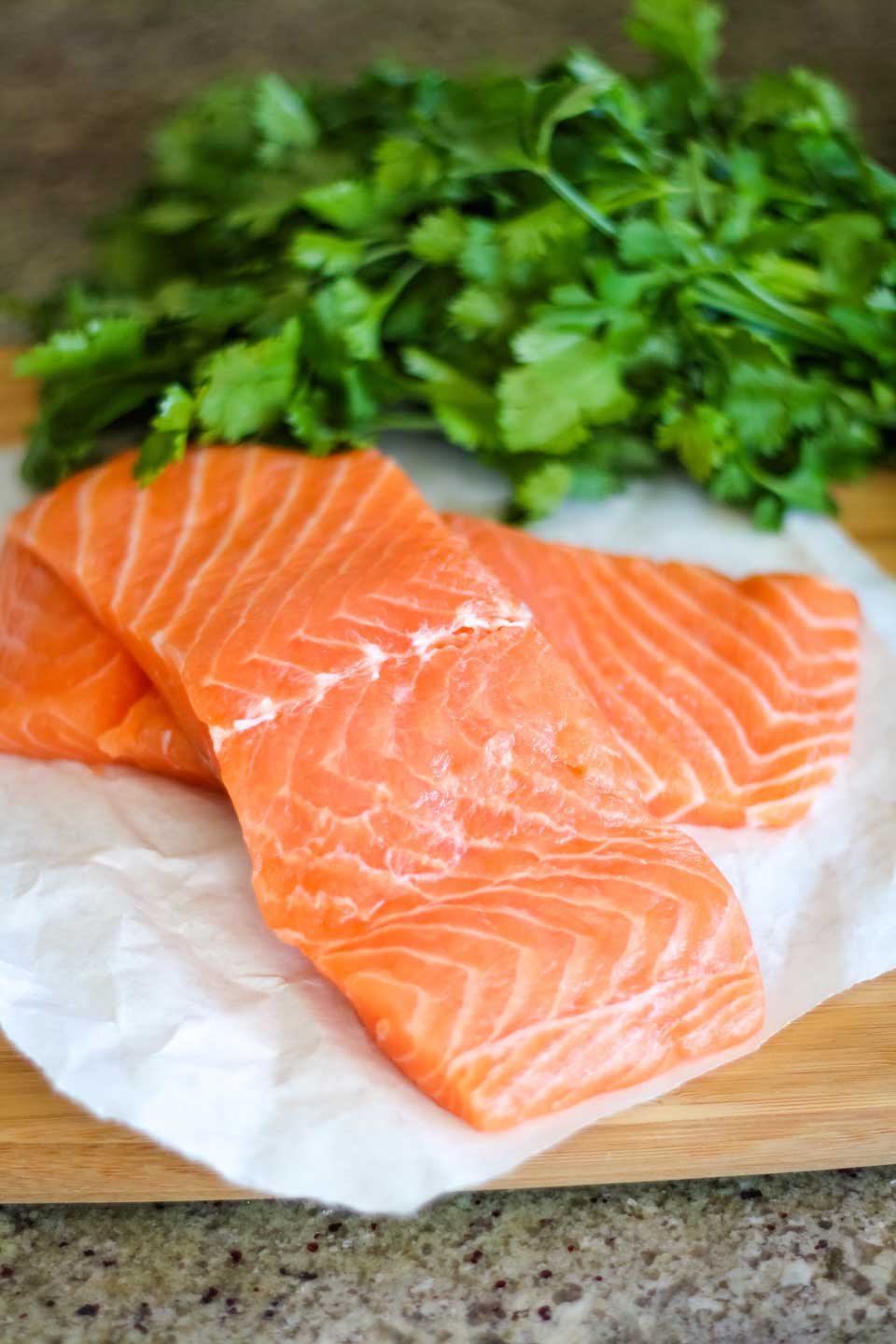 gorgeous fresh salmon filets on butcher paper, with a bunch of fresh parsley in the background