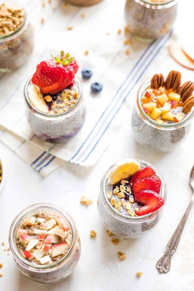 Pinnable image of several pre-portioned jars of Overnight Chia Pudding with different toppings.