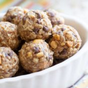 Closeup of small bowl filled with completed energy balls, laying on a colorful striped cloth.