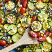 Sauteed vegetables, still in pan, with wooden spoon scooping in.