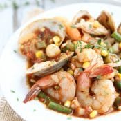 Side closeup of stew in a white-rimmed bowl so you can really see the individual shrimp, clams and other seafood.