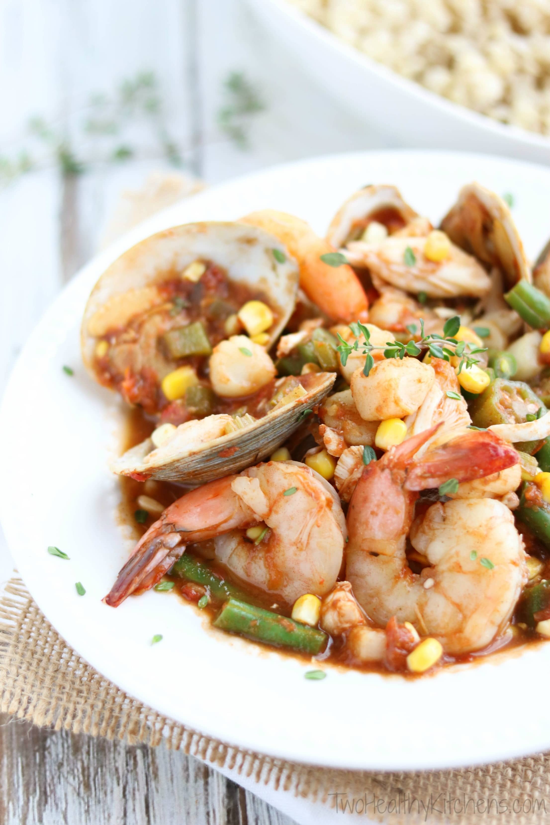 Side closeup of stew in a white-rimmed bowl so you can really see the individual shrimp, clams and other seafood.