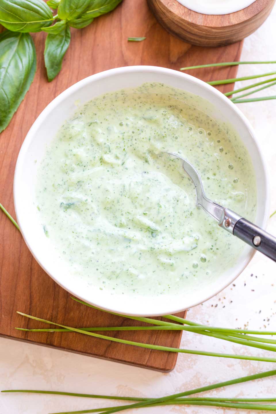 Overhead of white bowl with the finished tzatziki sauce, with a black-handled spoon in it.