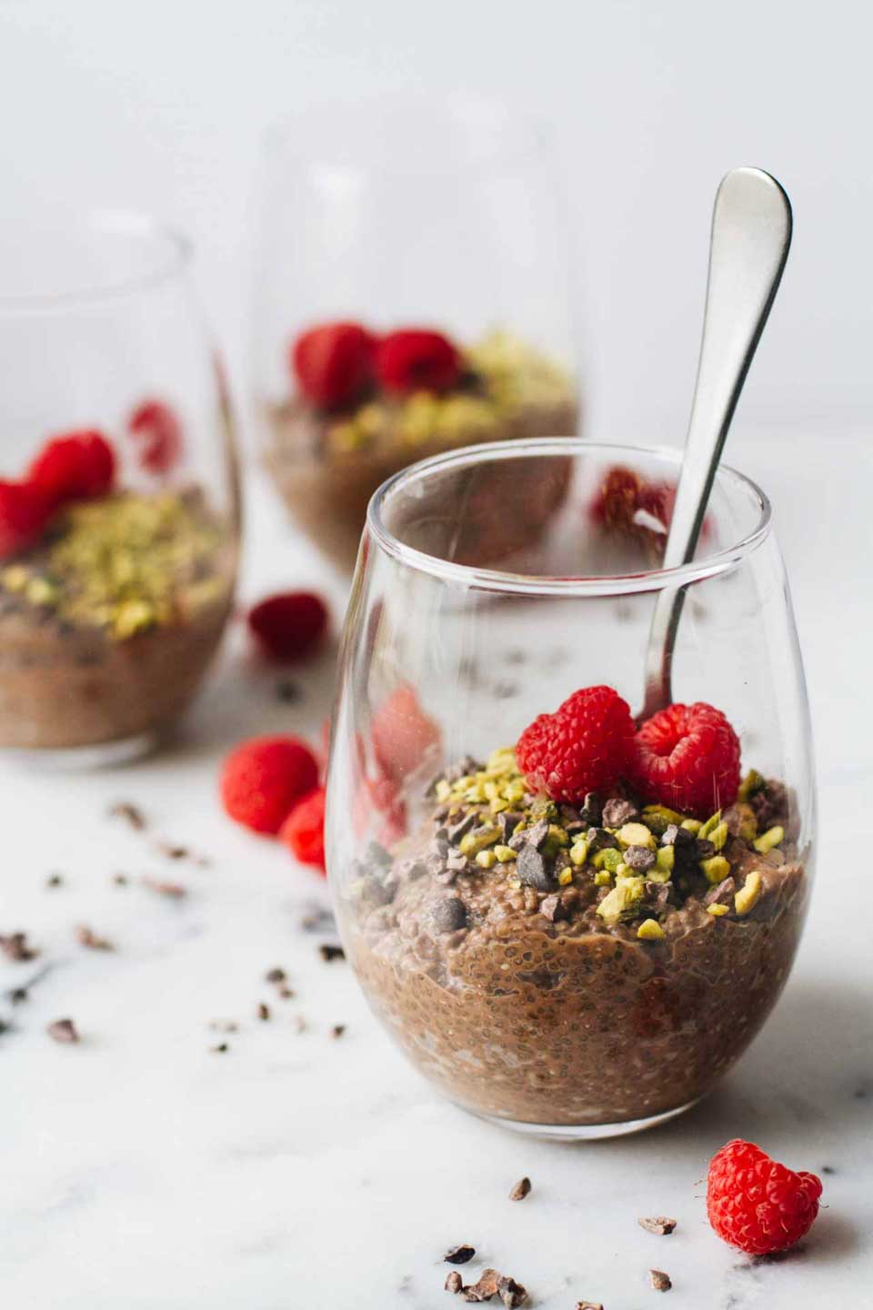 3 stemless wine glasses half full of pudding, with a spoon stuck in the front glass.