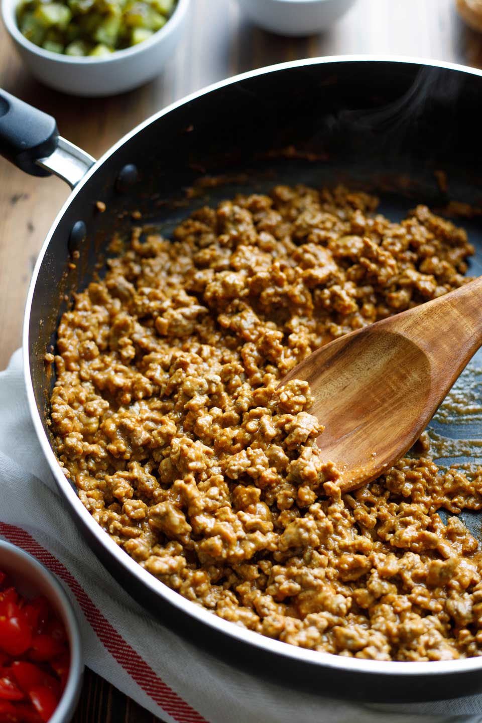 pan with extra lean ground beef mixture being stirred with wooden spoon